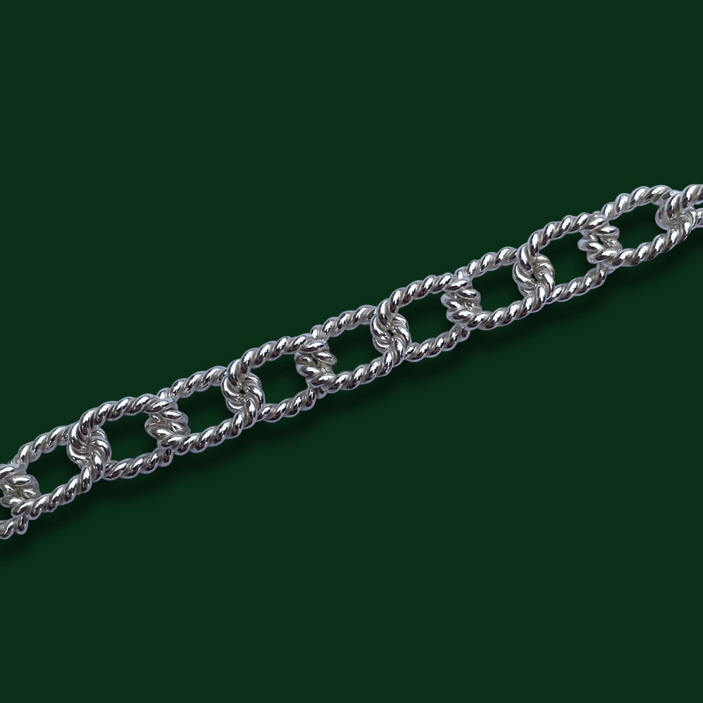 A close up of Timio's Jamboree style to show the twisted, squared oval links on a dark green background.