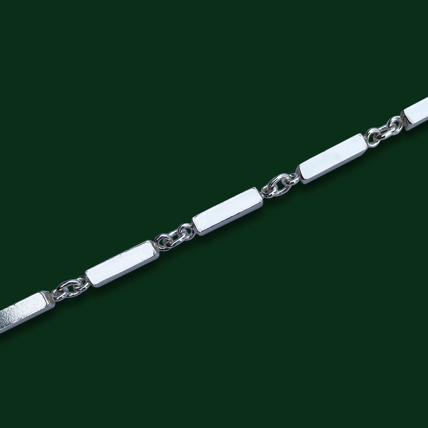A close up of Timio's Axia style on a dark green background, to emphasize its ingot-like bar links joined by circle links.