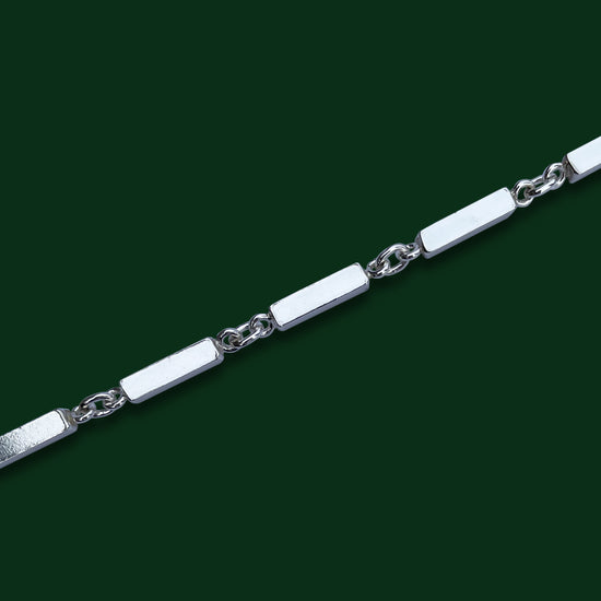 A close up of Timio's Axia style on a dark green background, to emphasize its ingot-like bar links joined by circle links.