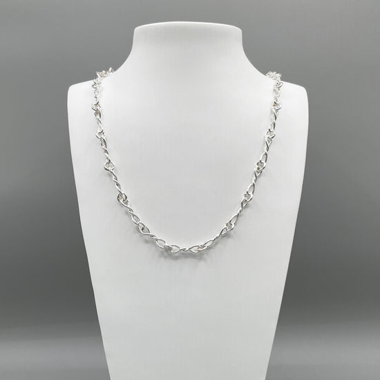 A photo of the Bolero chain displayed on a white bust in front of a grey background.