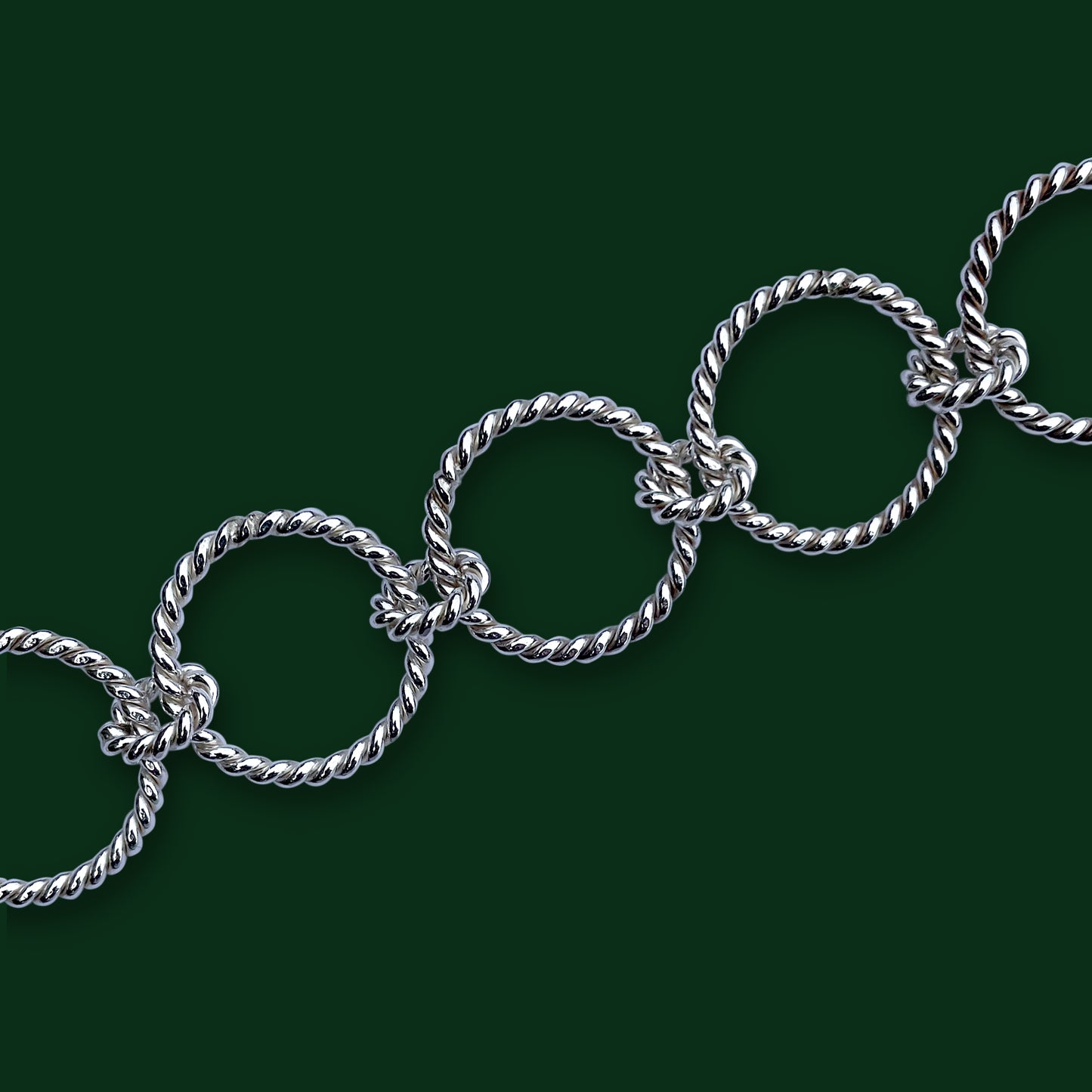 A close up on Timio's Carousel chain links on dark green background.