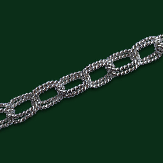 A close up of Timio's Gala chain on a dark green background to emphasize the detail of the pairs of twisted oval links that make up this style.