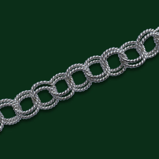 A close up of Timio's Laurel chain on a dark green background to emphasize the pairs of twisted circles linked together.