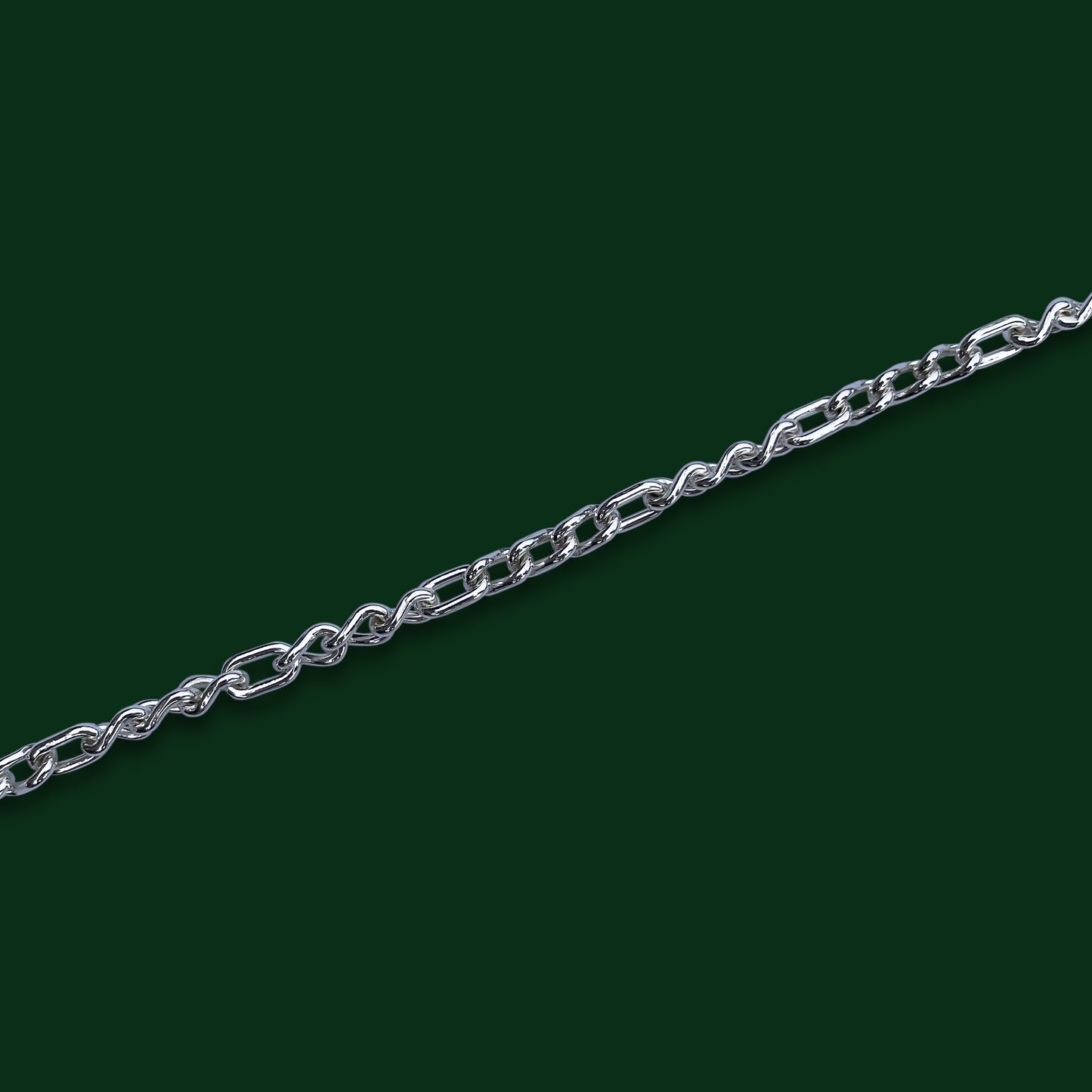 A close up of Timio's Trias chain on a dark green background, emphasizing the three curved links to every one small oval link pattern.